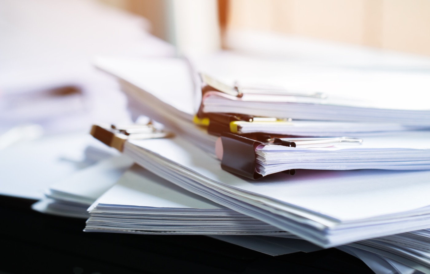 Stacks of clipped research documents and reports